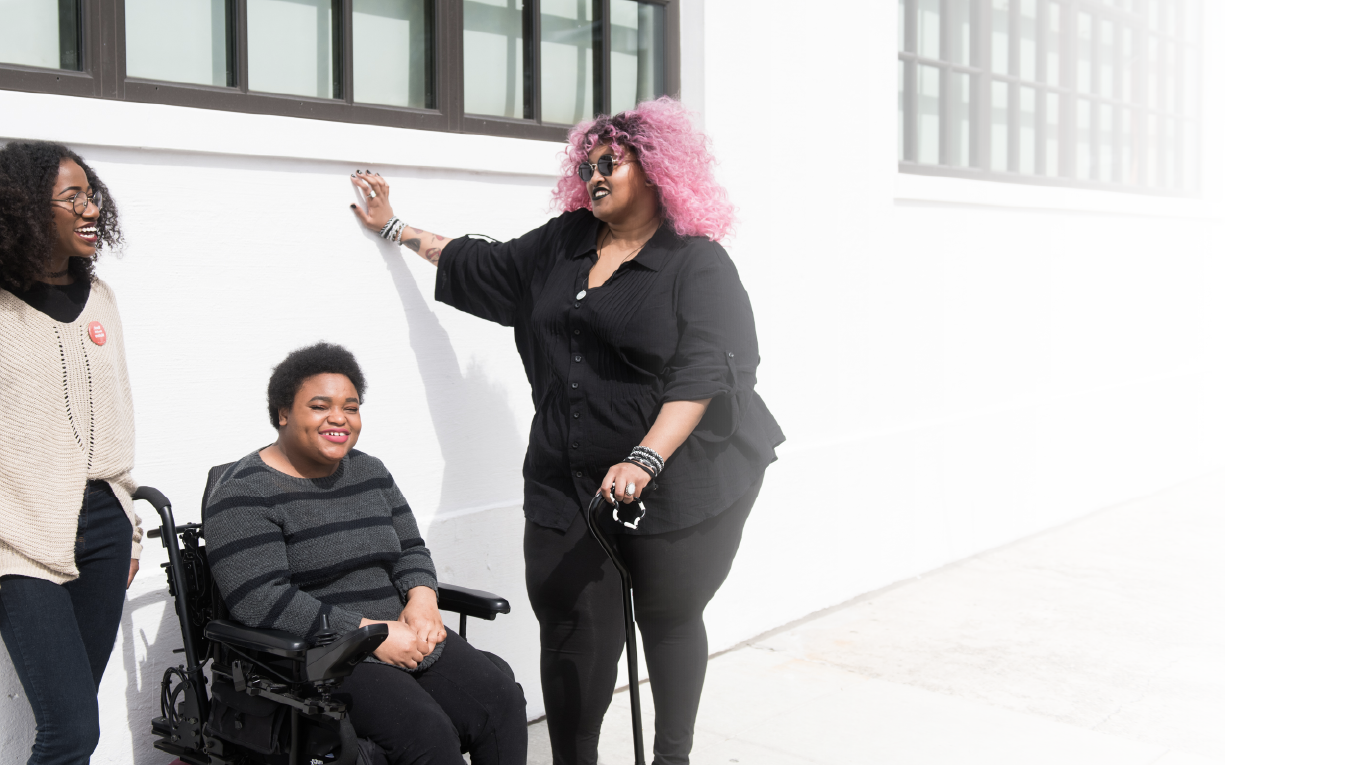 three girls one in a wheel chair and one blind laughing together