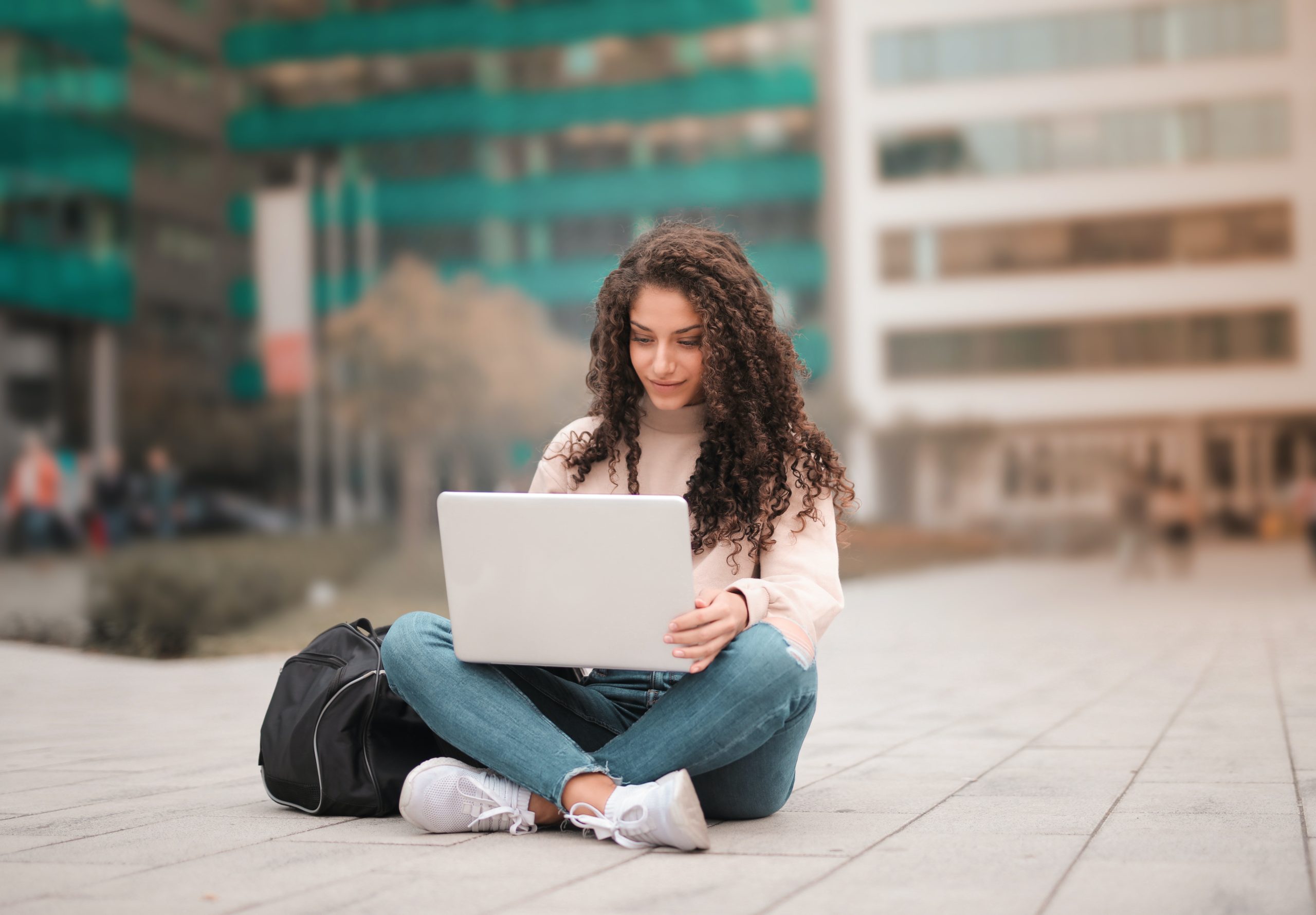 girl sitting down with laptop in courtyard